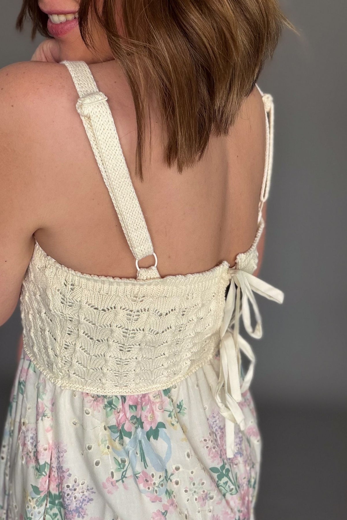 Crochet bodice floral midi dress with adjustable straps and tiered ruffle skirt showing a closeup of the adjustable straps and tie back