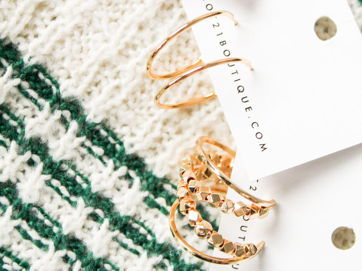 Gold hoop earrings on a textured fabric background with '21 Boutique' card.