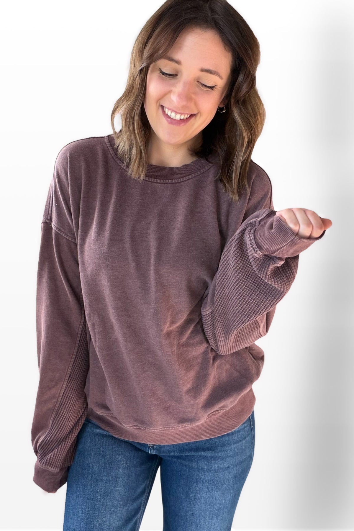 Woman wearing a cherry sweatshirt and blue jeans on a white background