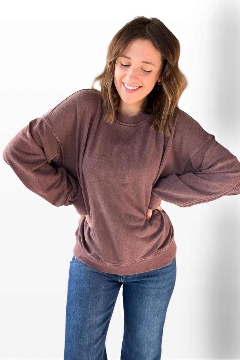 Woman wearing a deep cherry sweatshirt and blue jeans on a white background