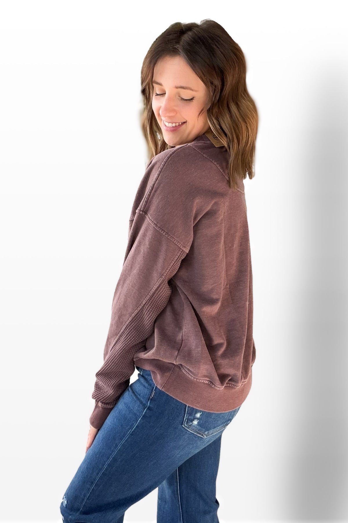 Woman wearing a cherry sweatshirt and blue jeans on a white background
