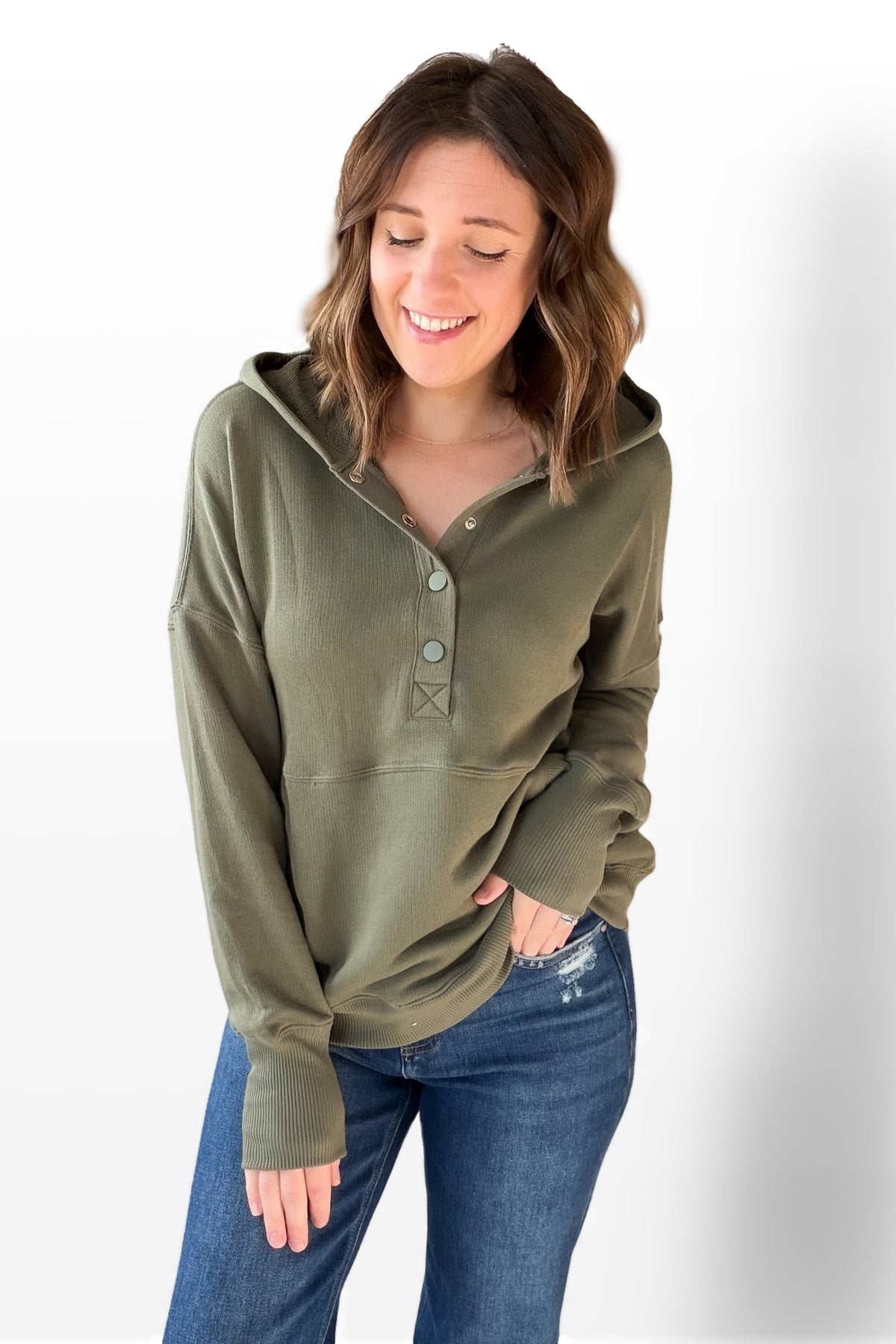 Woman wearing an olive green long-sleeve shirt with a hood on a white background