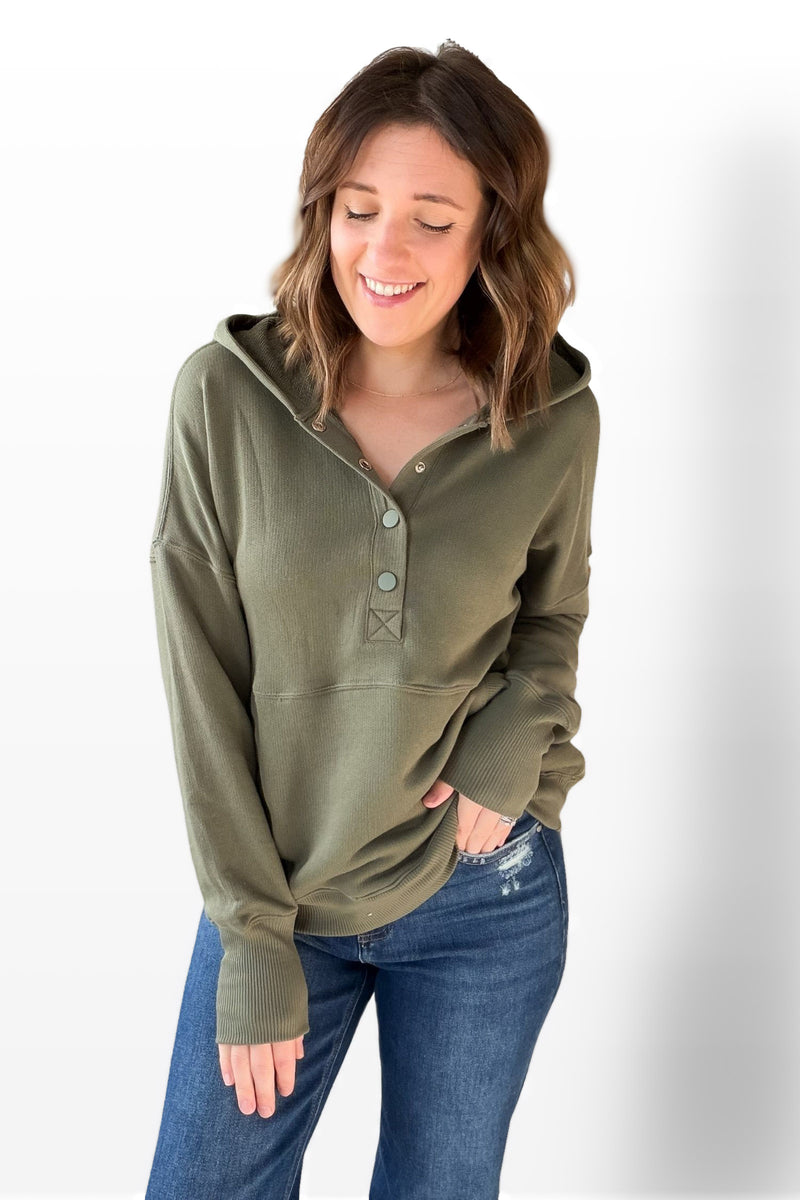 Woman wearing an olive green long-sleeve shirt with a hood on a white background