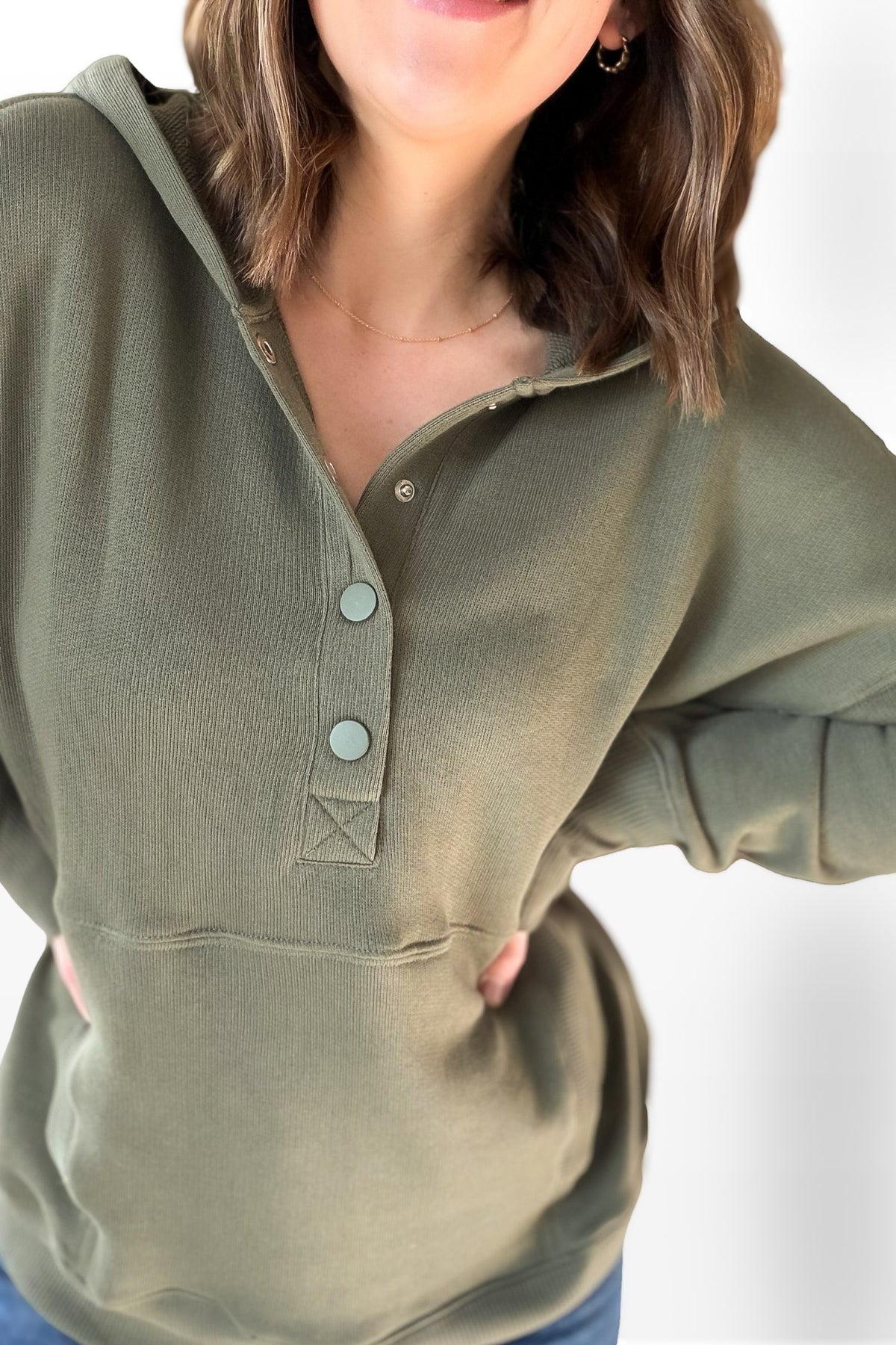 Person wearing a green long-sleeve shirt with buttons on a white background