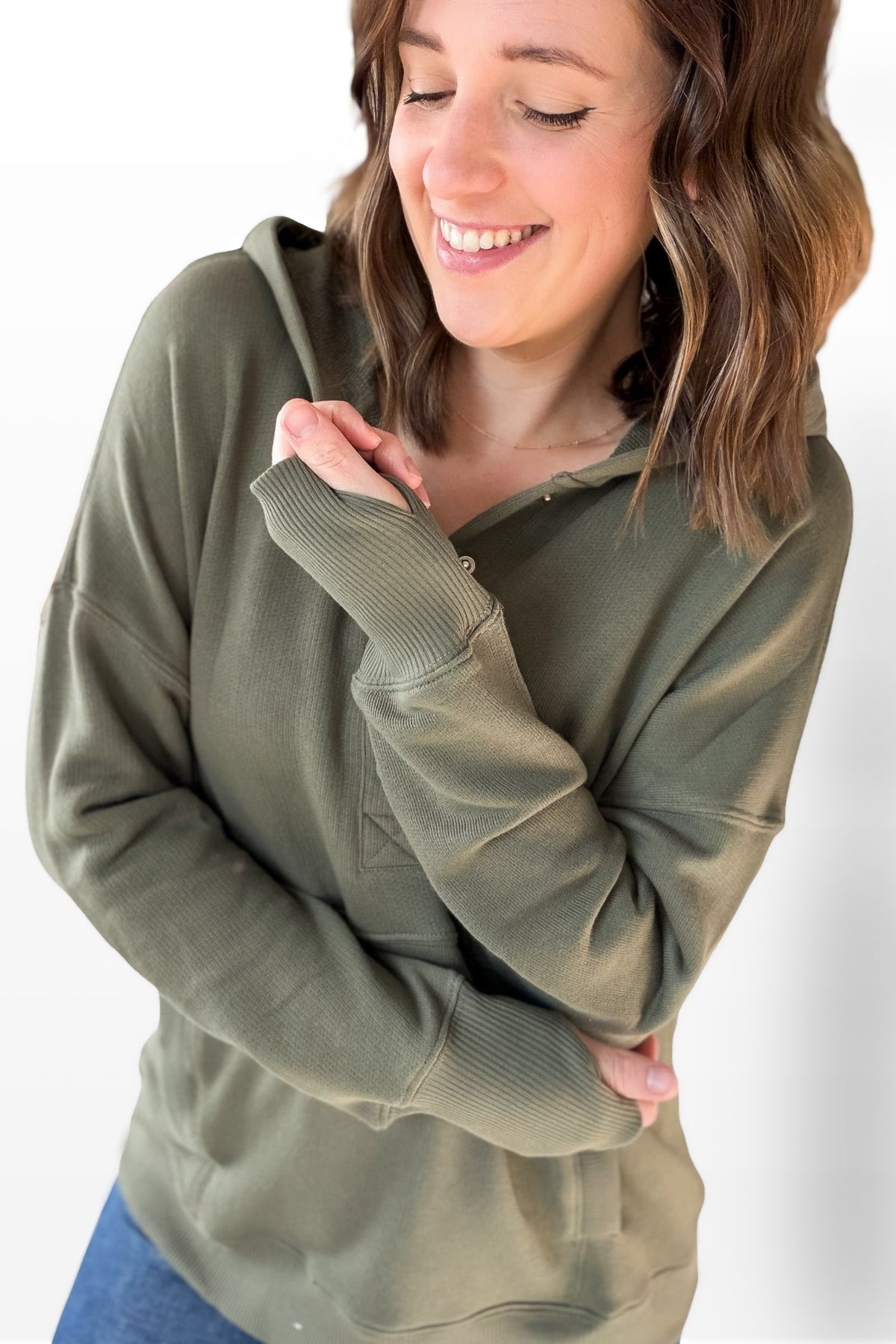 Woman wearing a green hoodie against a white background