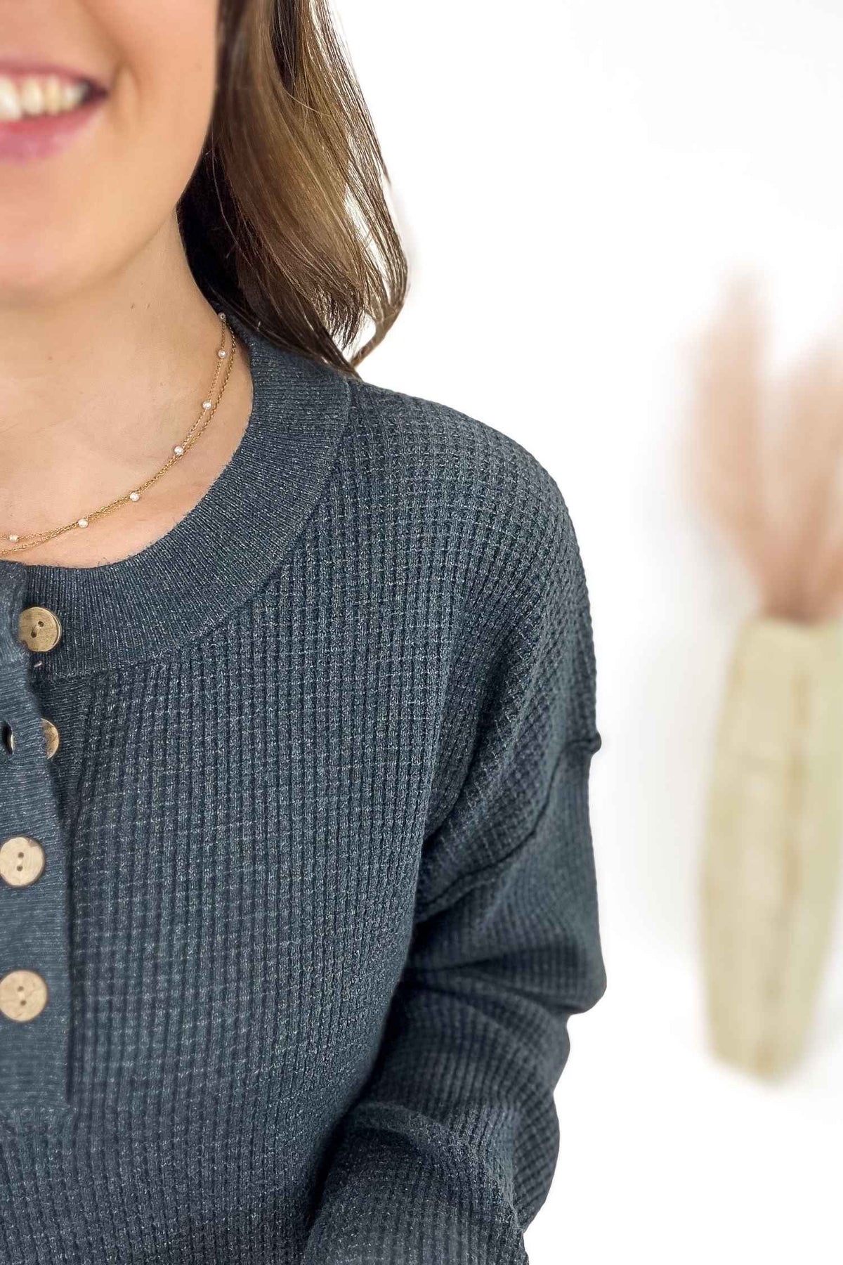Person wearing a textured blue shirt with buttons on a white background