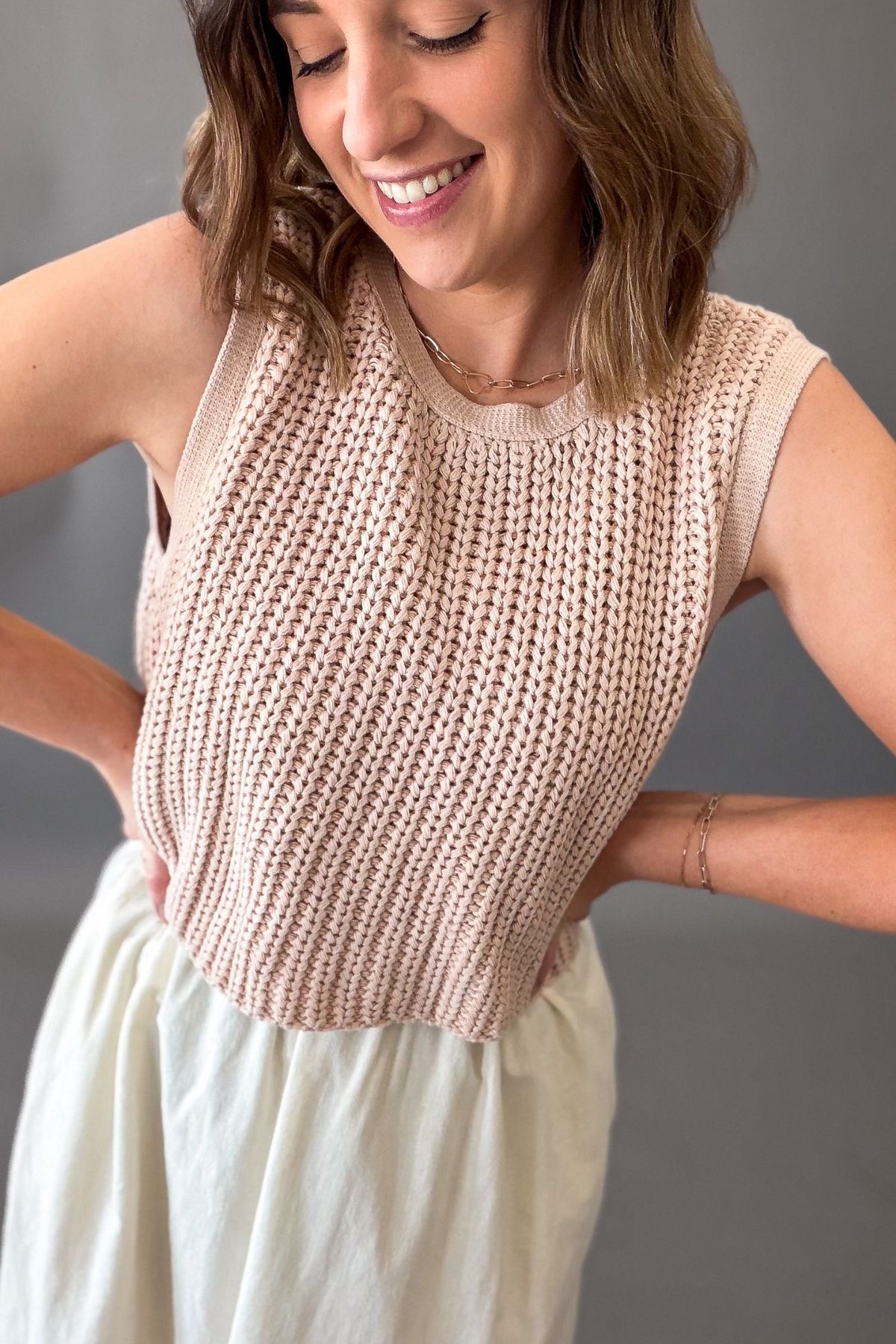 Woman wearing a dusty blush chunky sweater twofer midi dress with layered knit top and flowy lined skirt with side slits