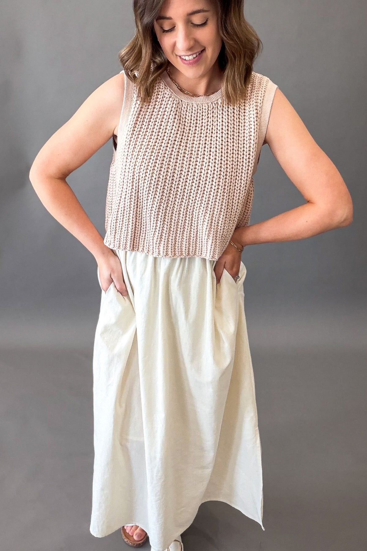 Woman wearing a dusty blush chunky sweater twofer midi dress with layered knit top and flowy lined skirt with side slits