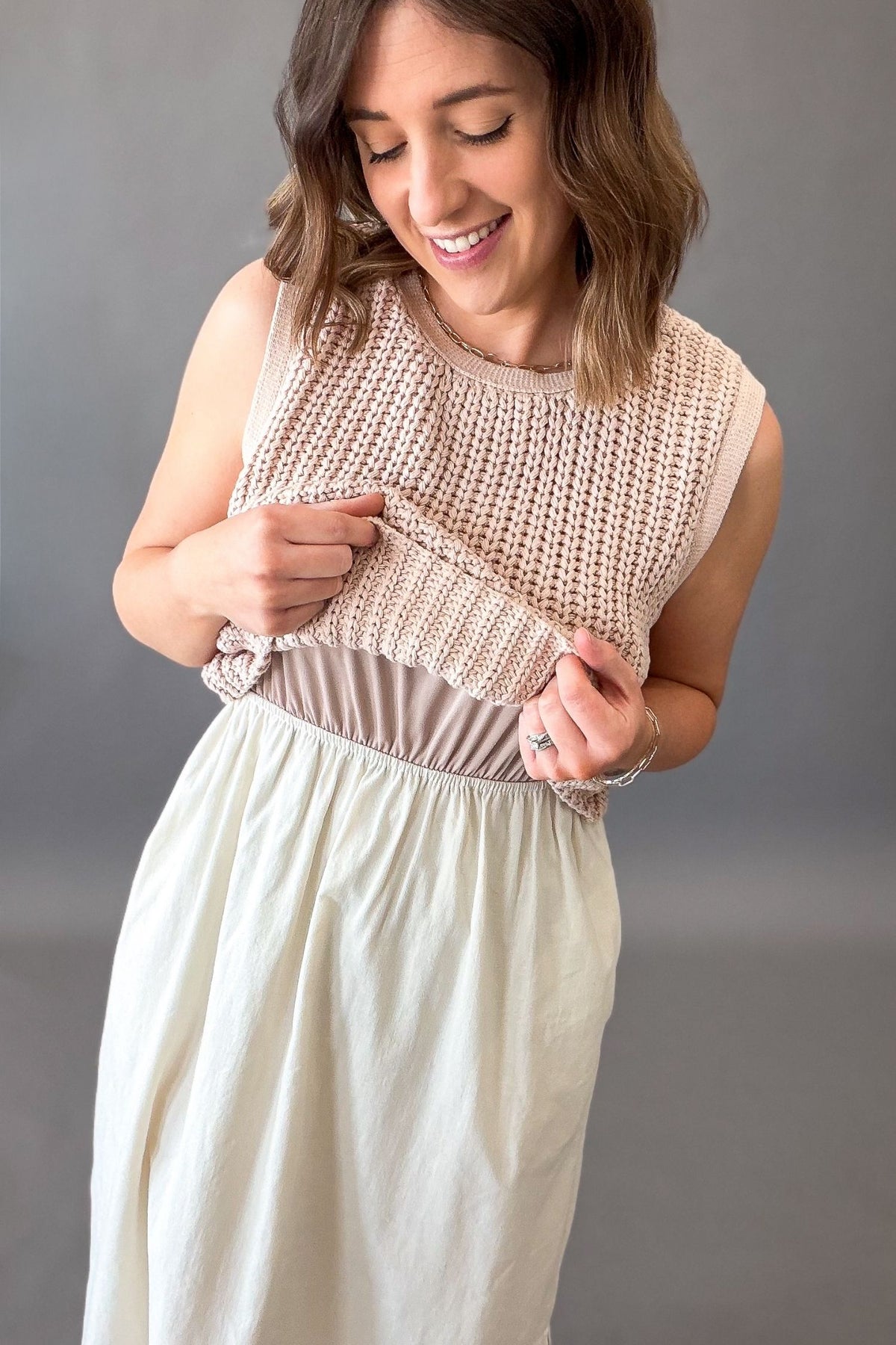 Woman wearing a dusty blush chunky sweater twofer midi dress showing the lining under the tank