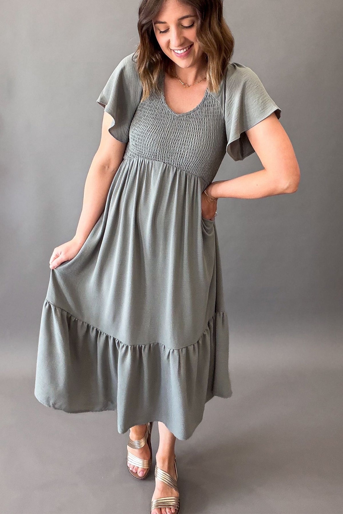 Woman wearing a dusty sage smocked midi dress with pockets