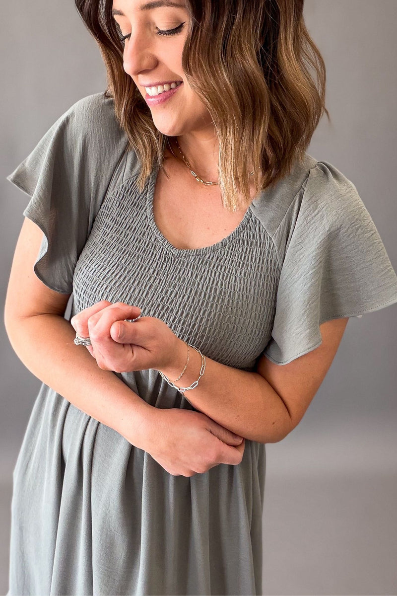 close up showing details of a Woman wearing a dusty sage smocked midi dress with pockets