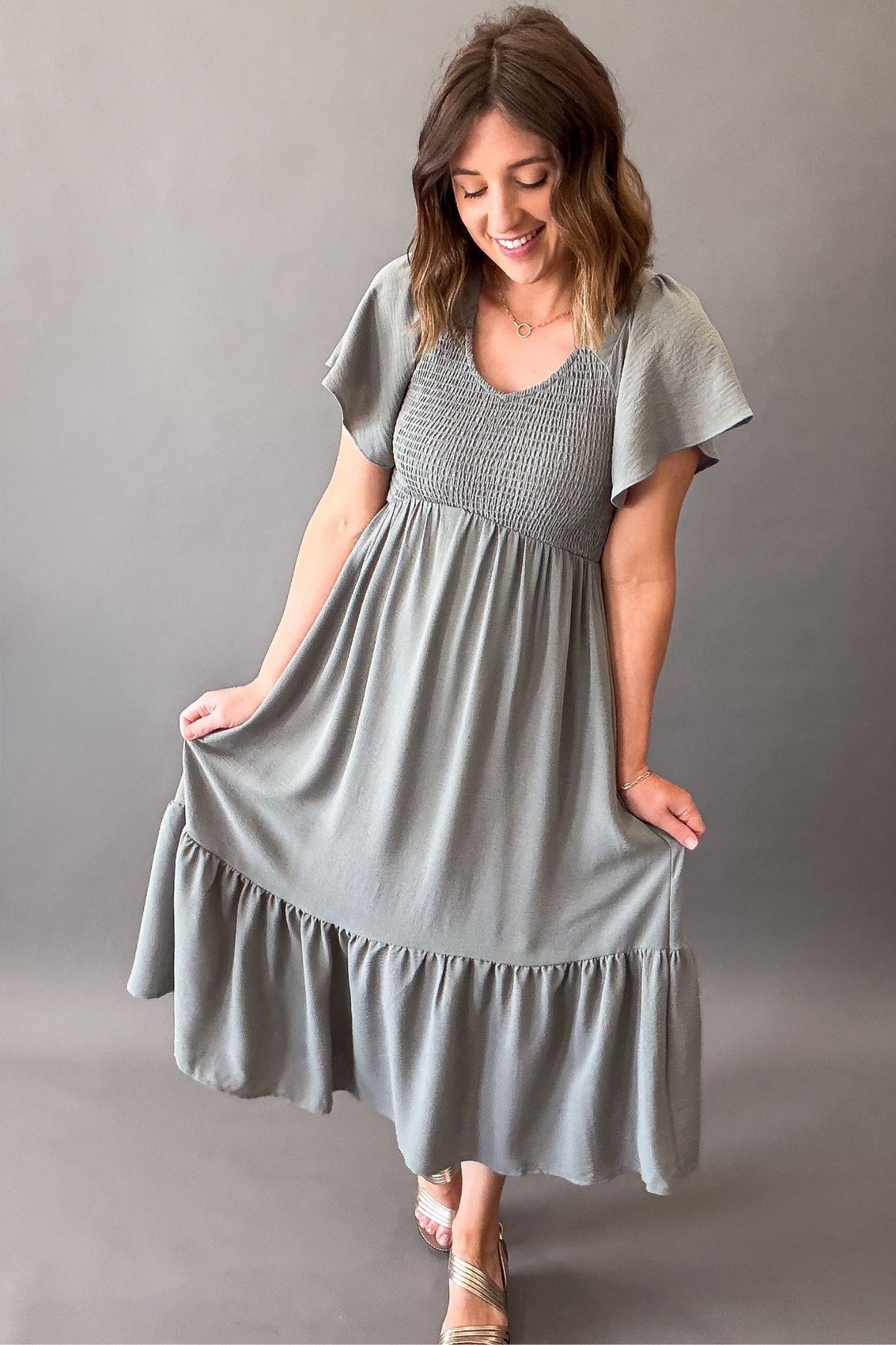 Woman wearing a dusty sage smocked midi dress with pockets