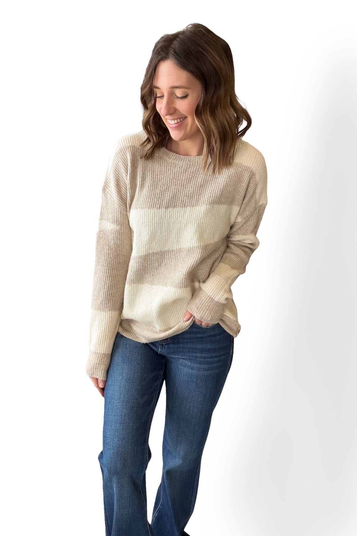 Woman wearing a beige sweater and blue jeans on a white background