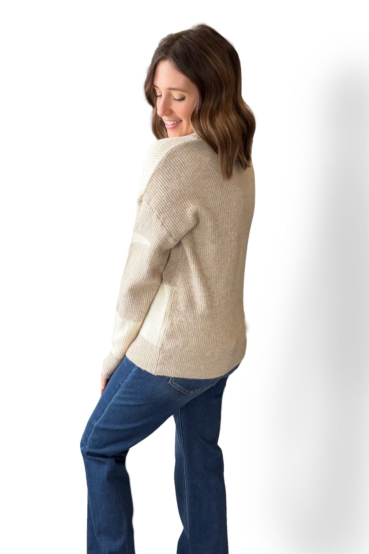 Woman wearing a beige sweater and blue jeans on a white background