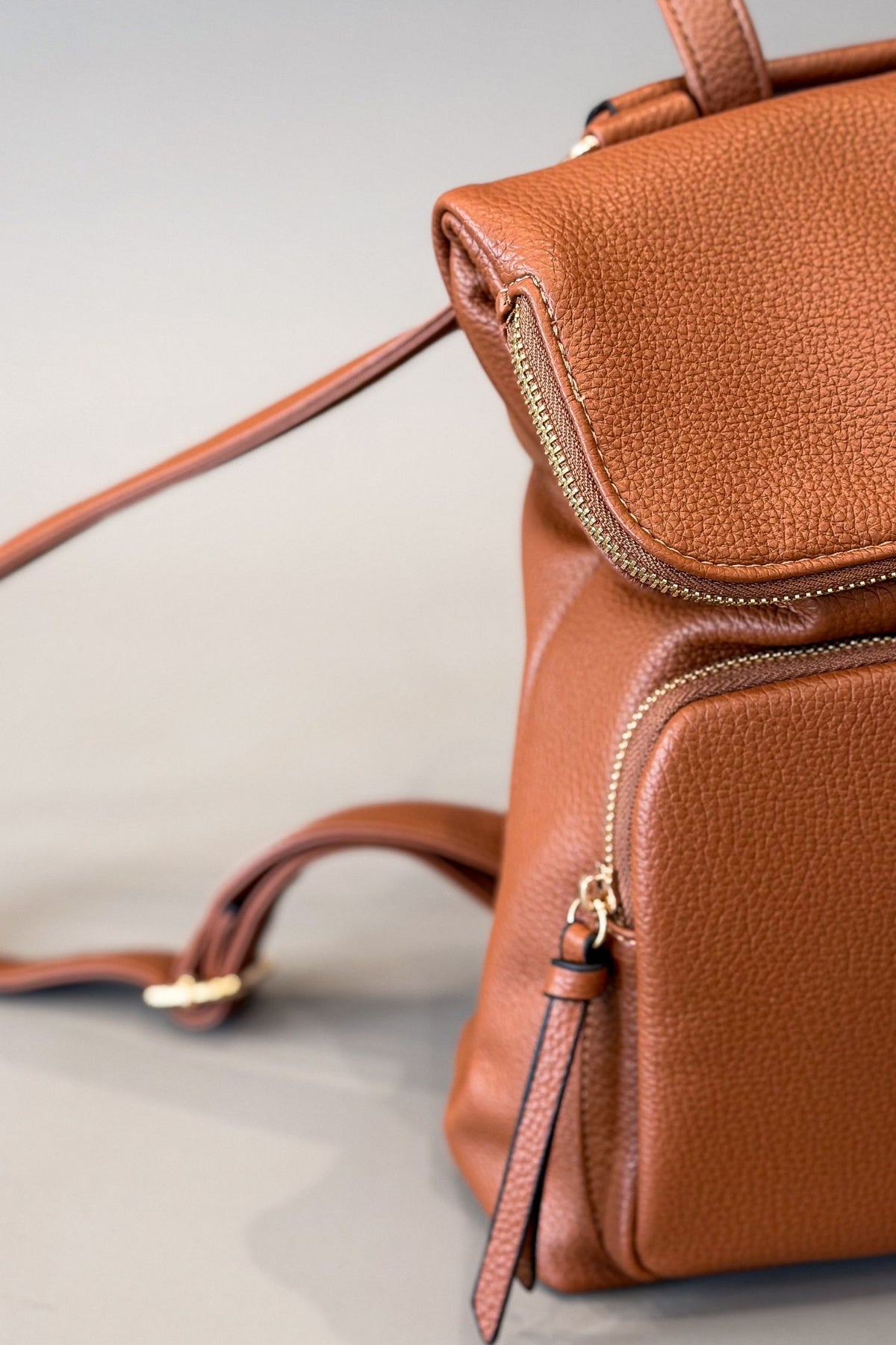 closeup photo of a brown backpack sitting on a grey background