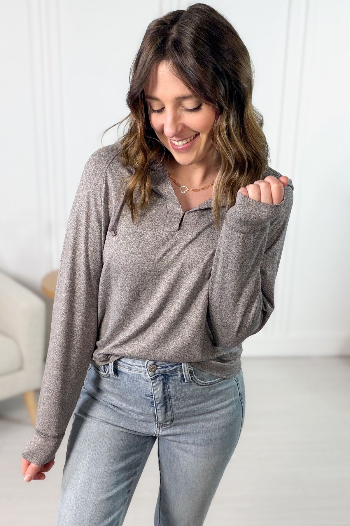 Woman wearing a mocha long-sleeve top and light blue jeans indoors.