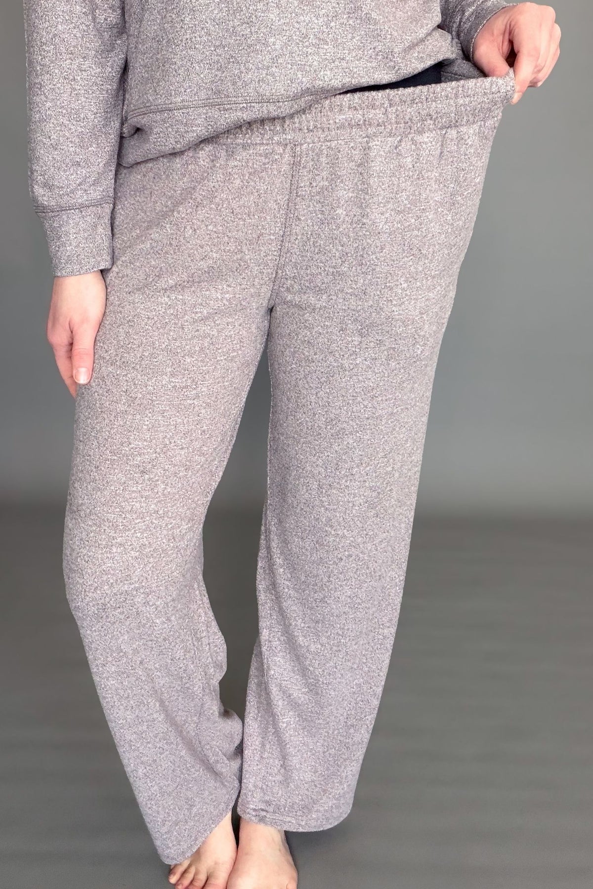 Women's espresso brushed lounge pants worn on a grey background showing stretch in the waistband