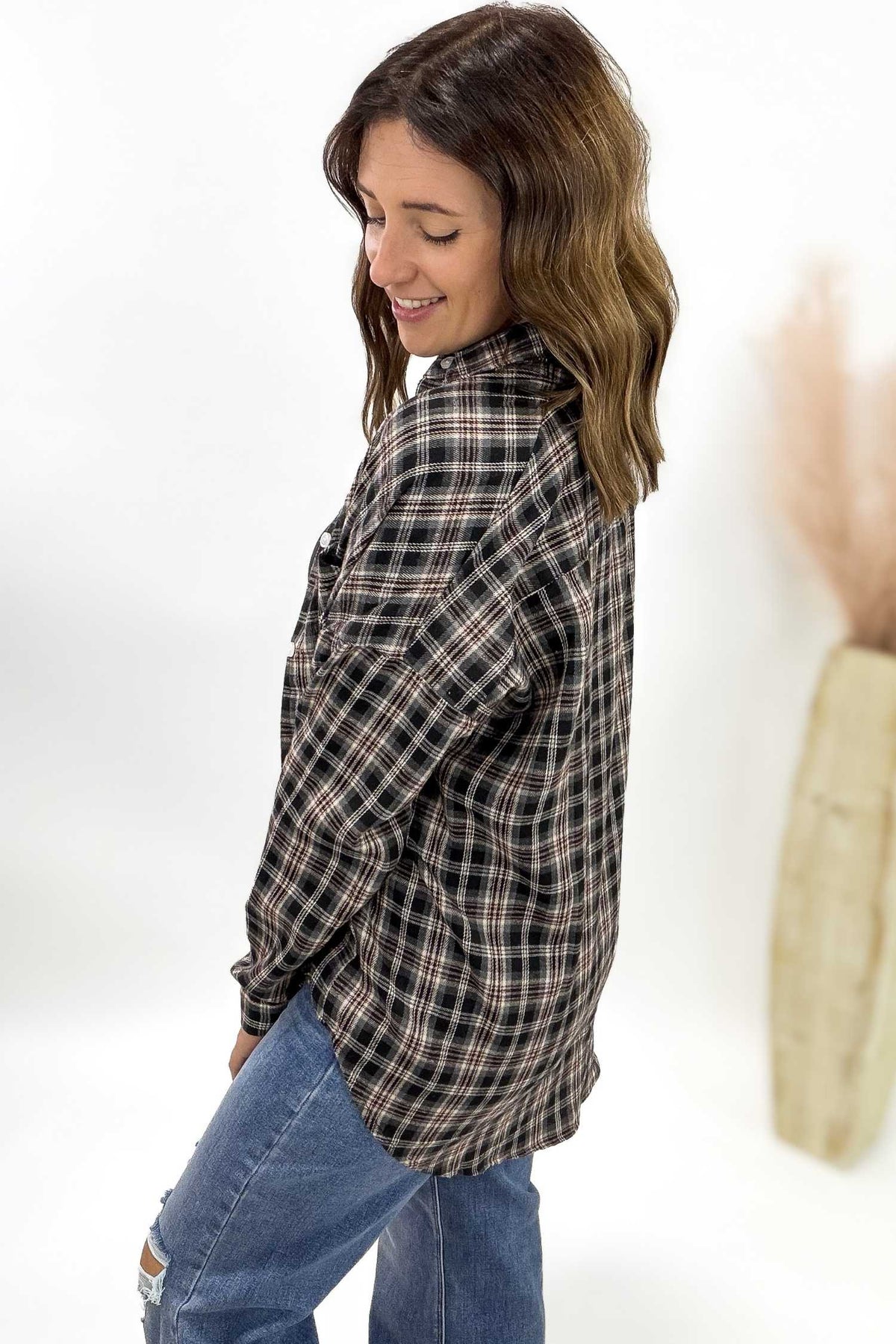 Woman wearing a plaid shirt and jeans against a white background