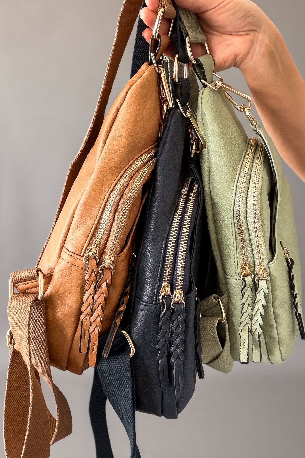 woman holding 3 crossbody bags showing the 2 zipper details