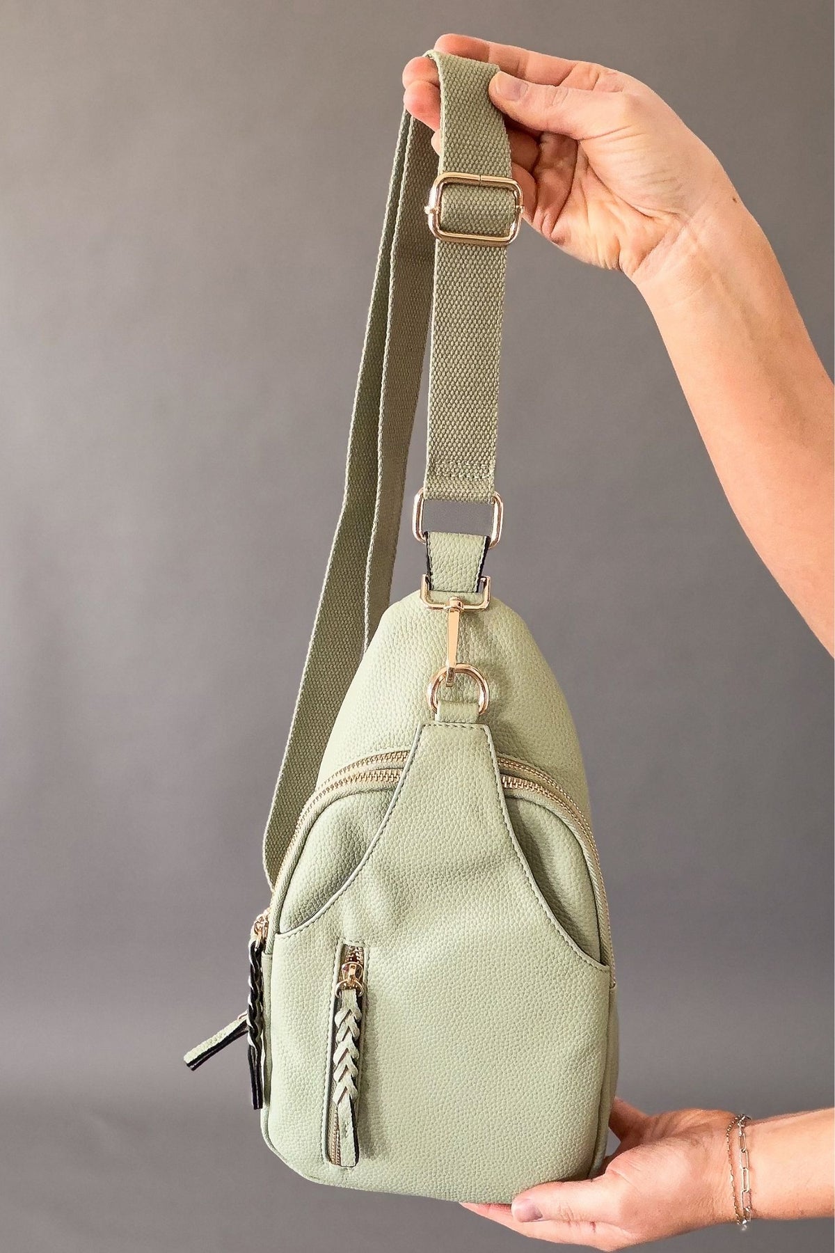 woman holding a light sage sling crossbody 