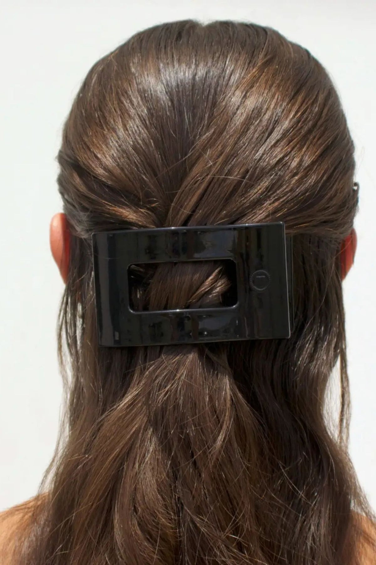 Black hair clip in a person's hair against a white background