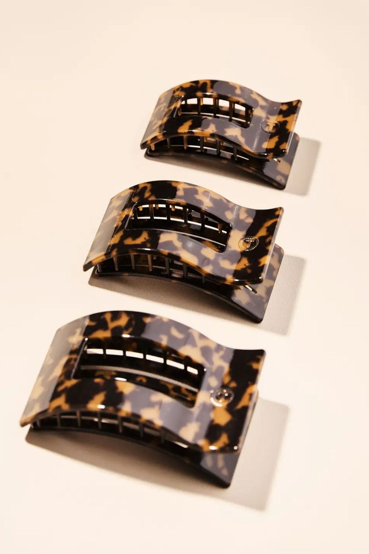 Set of three tortoiseshell patterned hair clips on a beige background