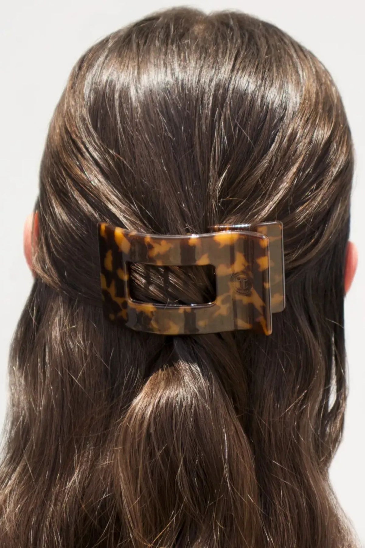 Tortoiseshell hair clip in a person's hair on a white background