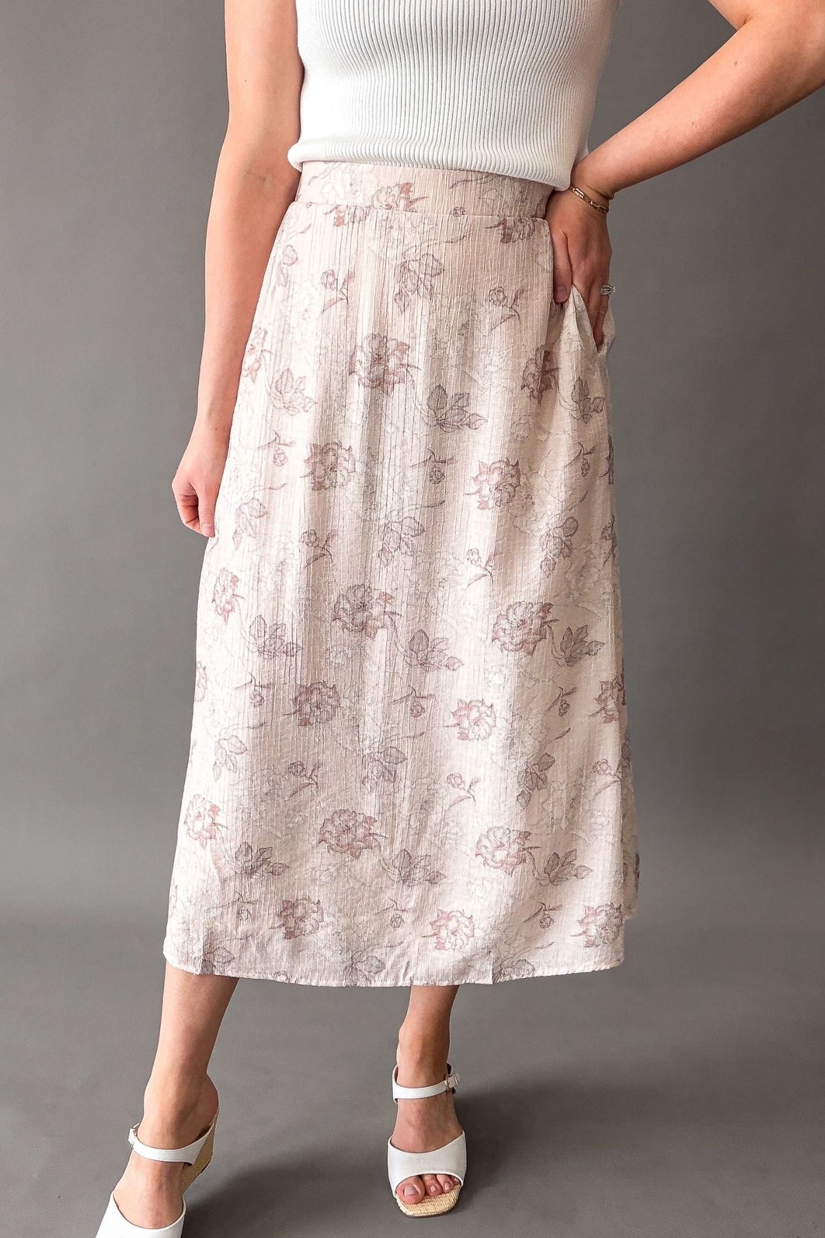 Woman wearing a blush floral midi skirt with elastic waistband and pockets, soft flowy lined skirt for women