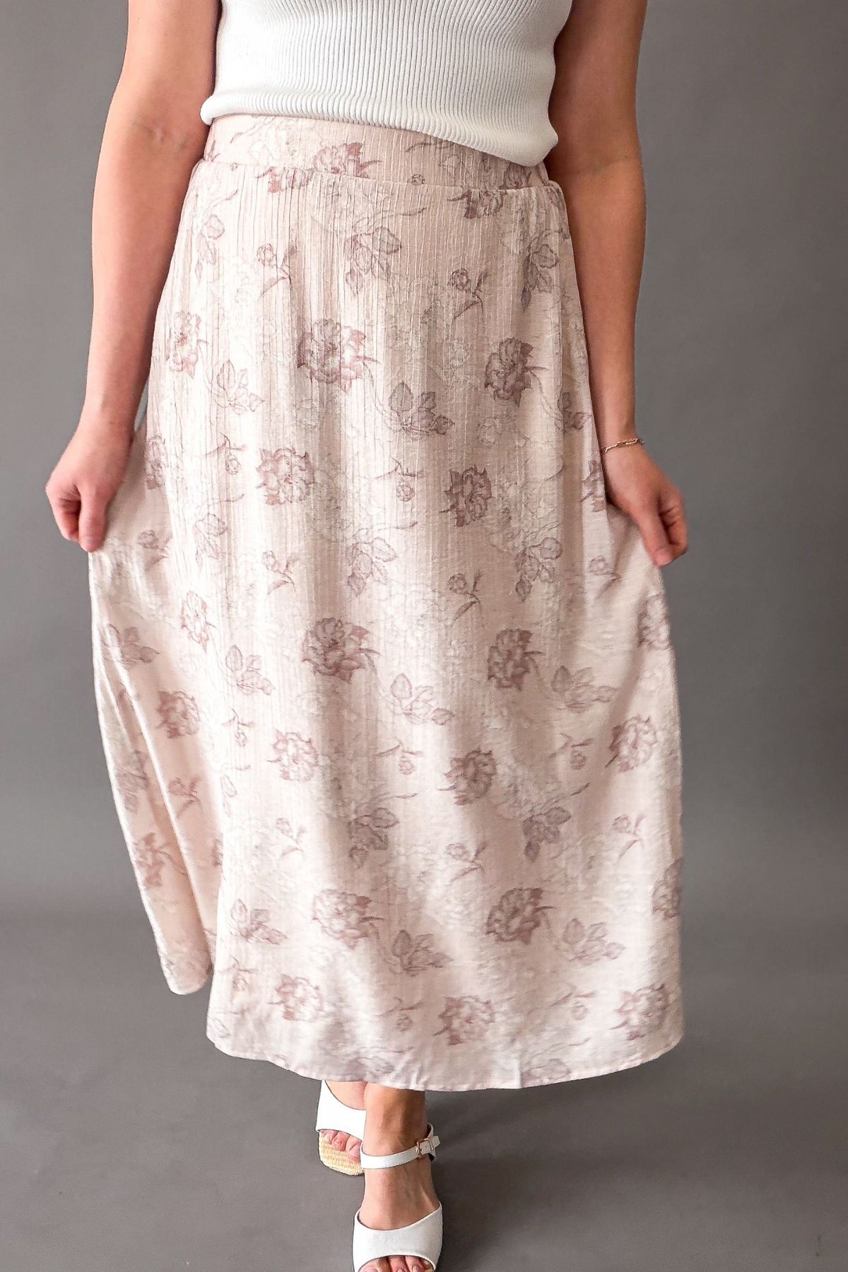 Woman wearing a blush floral midi skirt with elastic waistband and pockets, soft flowy lined skirt for women