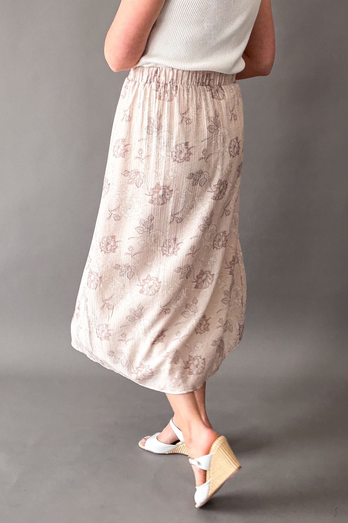 Woman wearing a blush floral midi skirt showing movement in the skirt