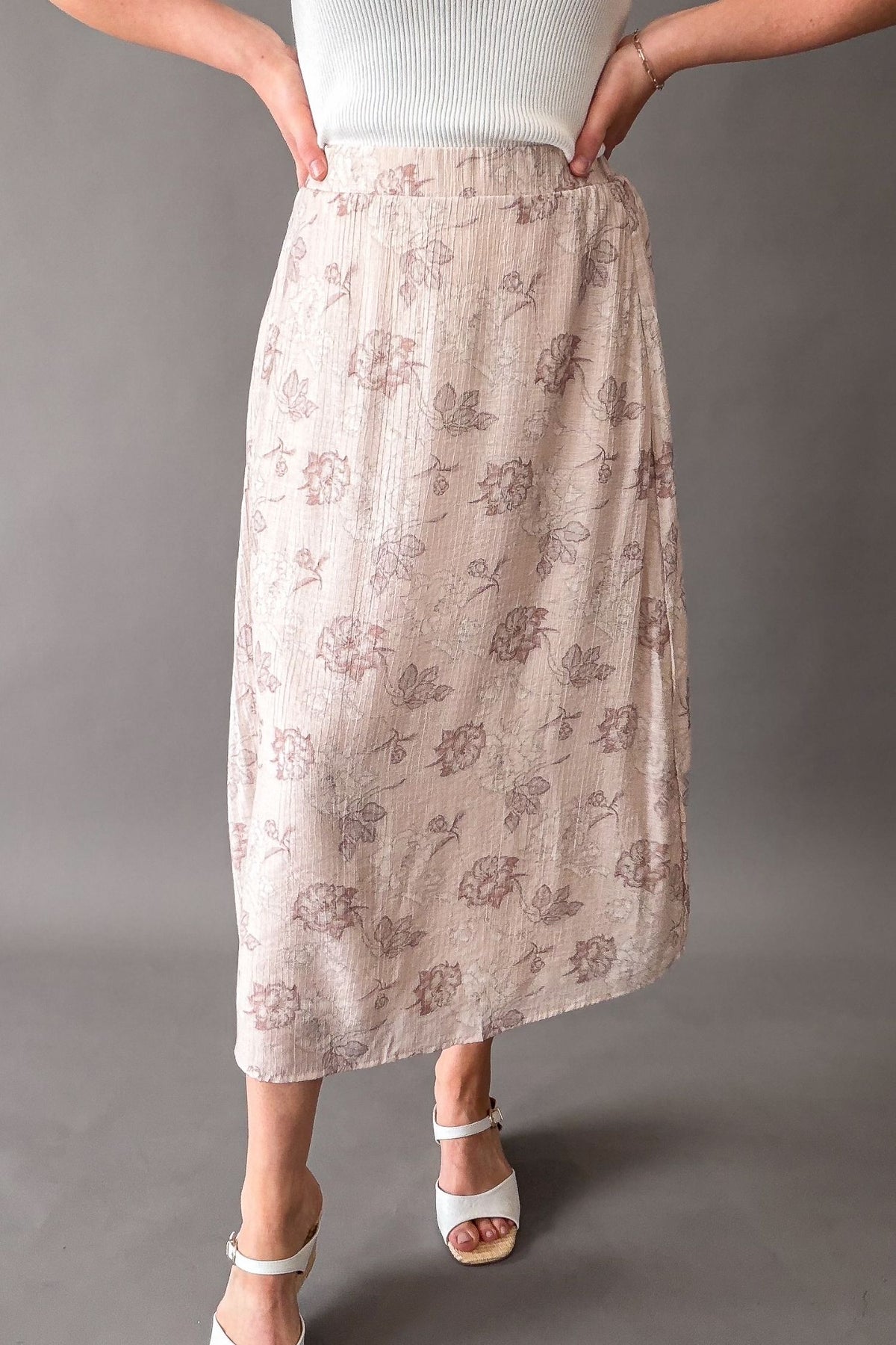 Woman wearing a blush floral midi skirt with elastic waistband and pockets, soft flowy lined skirt for women