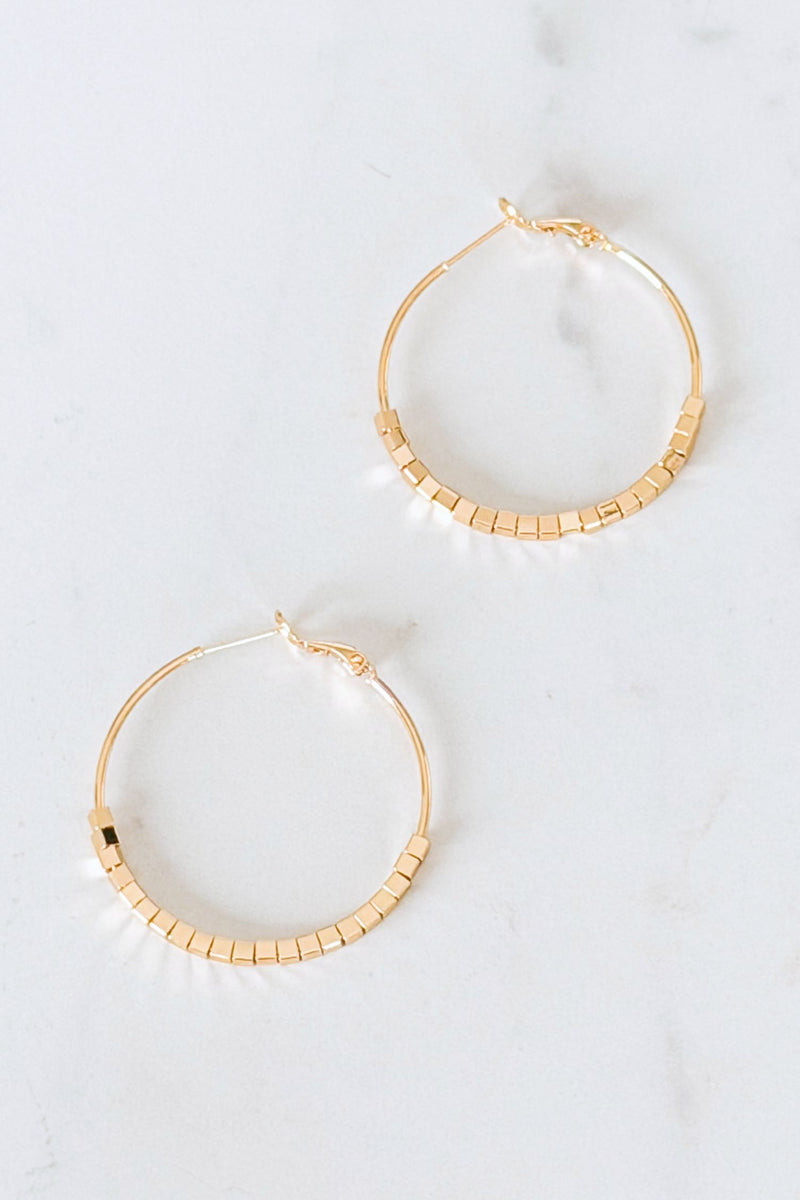 Gold hoop earrings with a textured design on a white background