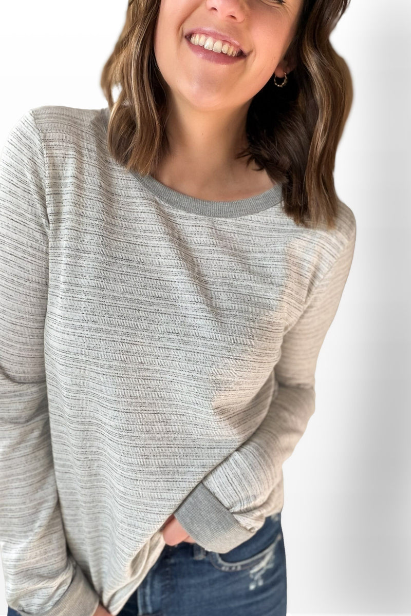 Woman wearing a gray and beige sweater with a plain background