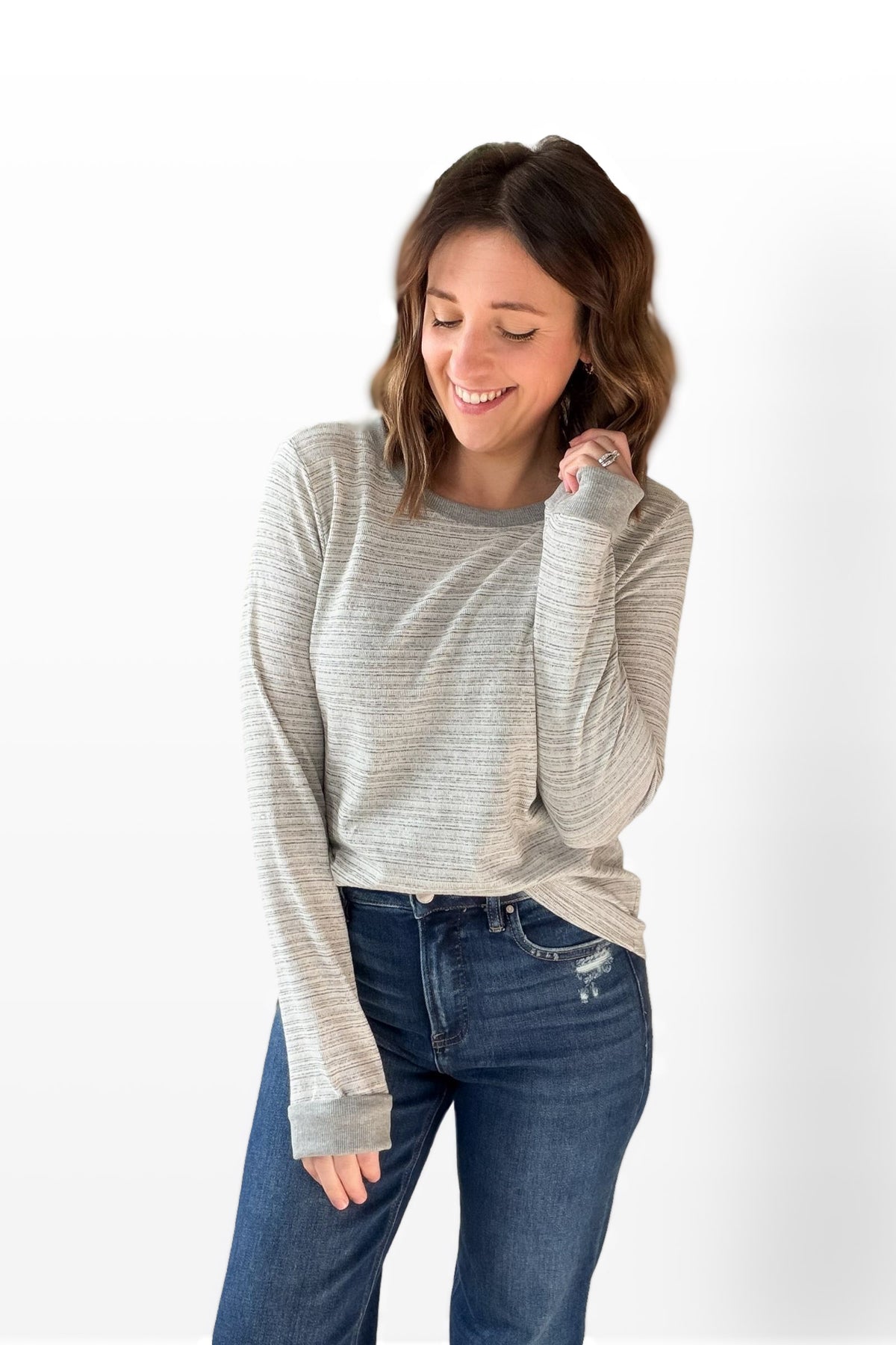 Woman wearing a striped long-sleeve top and blue jeans on a white background