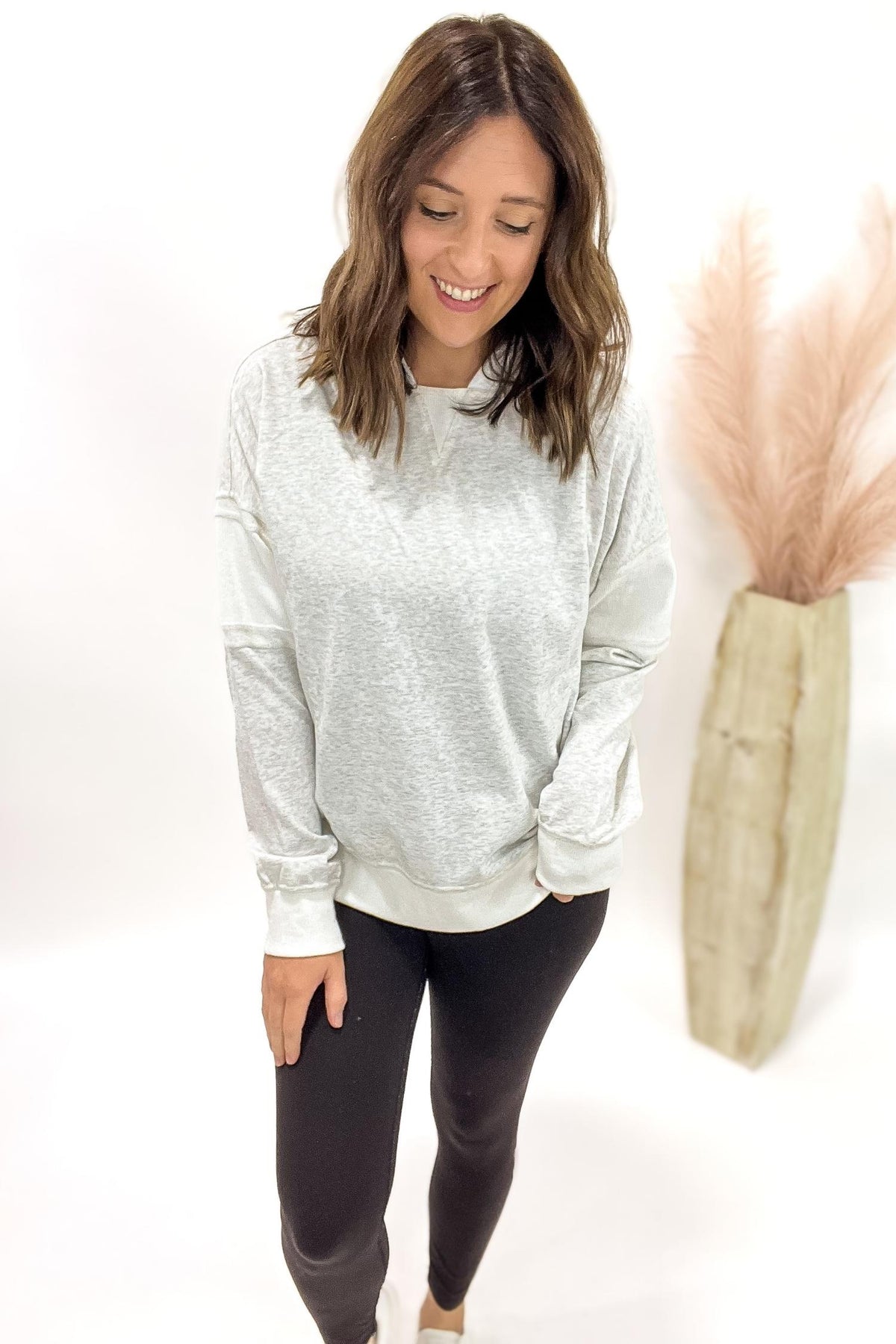 Woman wearing a heather grey hoodie with black leggings