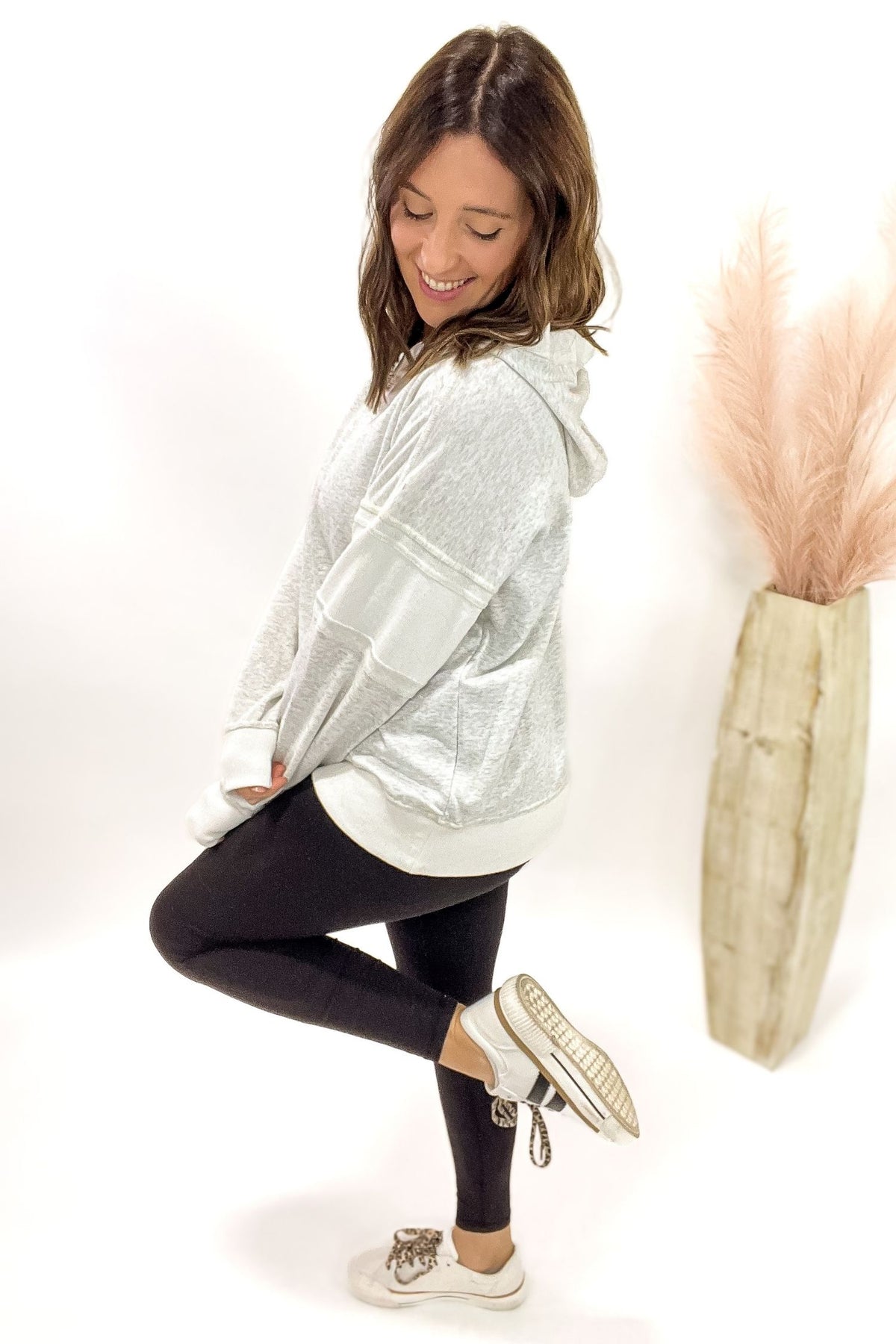Woman wearing a heather grey hoodie with black leggings