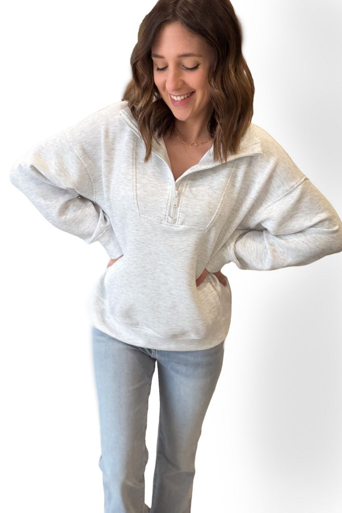 Woman wearing a light gray hoodie and light blue jeans on a white background