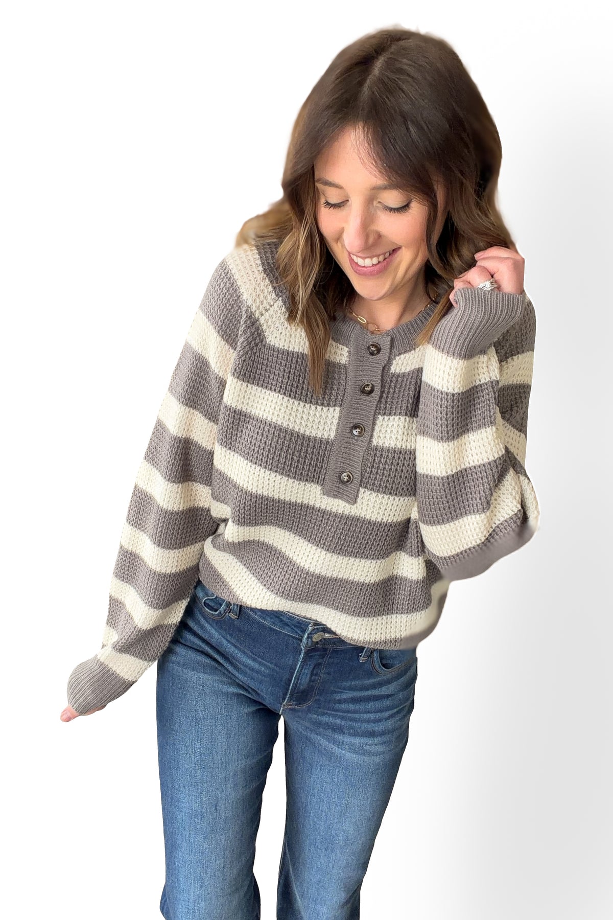 Woman wearing a gray and white striped sweater with blue jeans on a white background