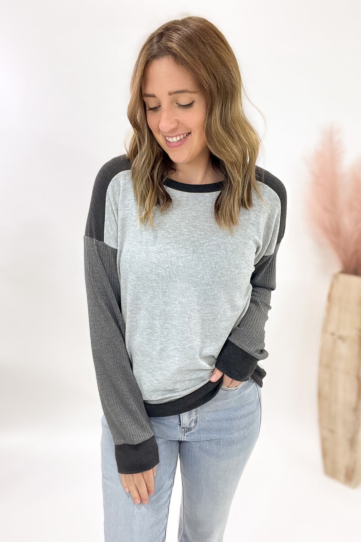 Woman wearing a gray and black long-sleeve top with a plain background
