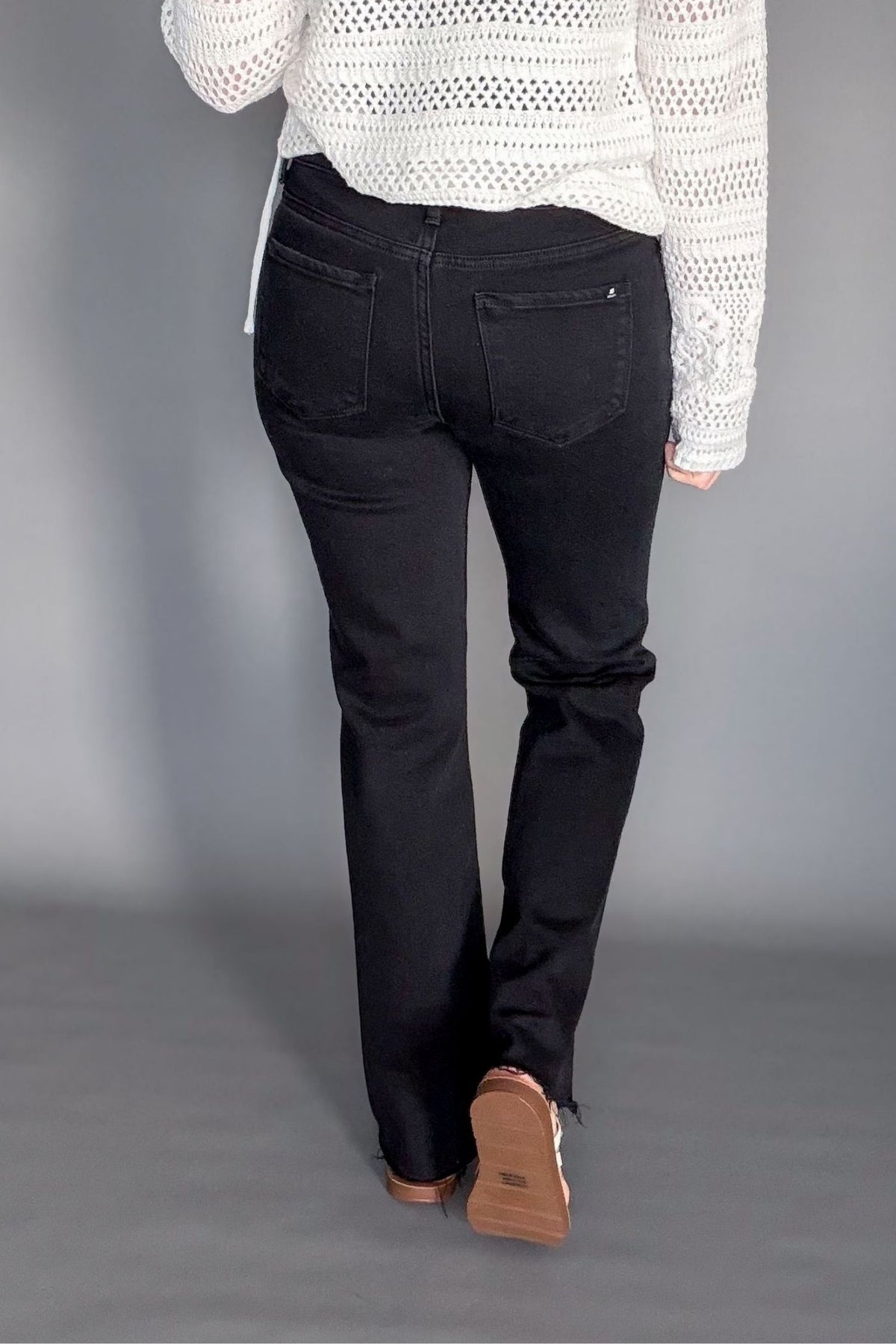 High rise black bootcut jeans styled with a sweater and sandals showing the back details