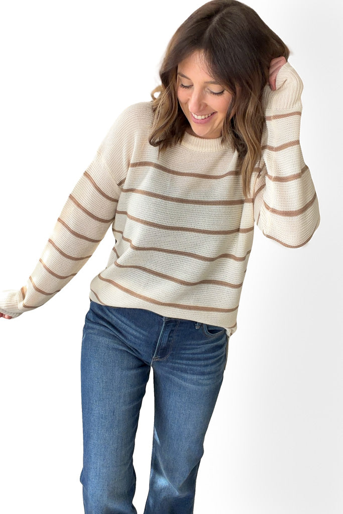 Woman wearing a striped sweater and jeans on a white background
