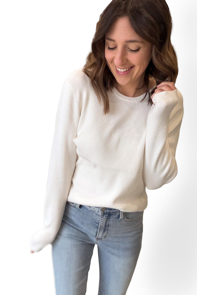 Woman wearing a white sweater and light blue jeans on a white background