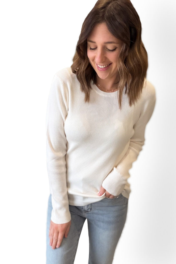 Woman wearing a white sweater and light blue jeans on a white background