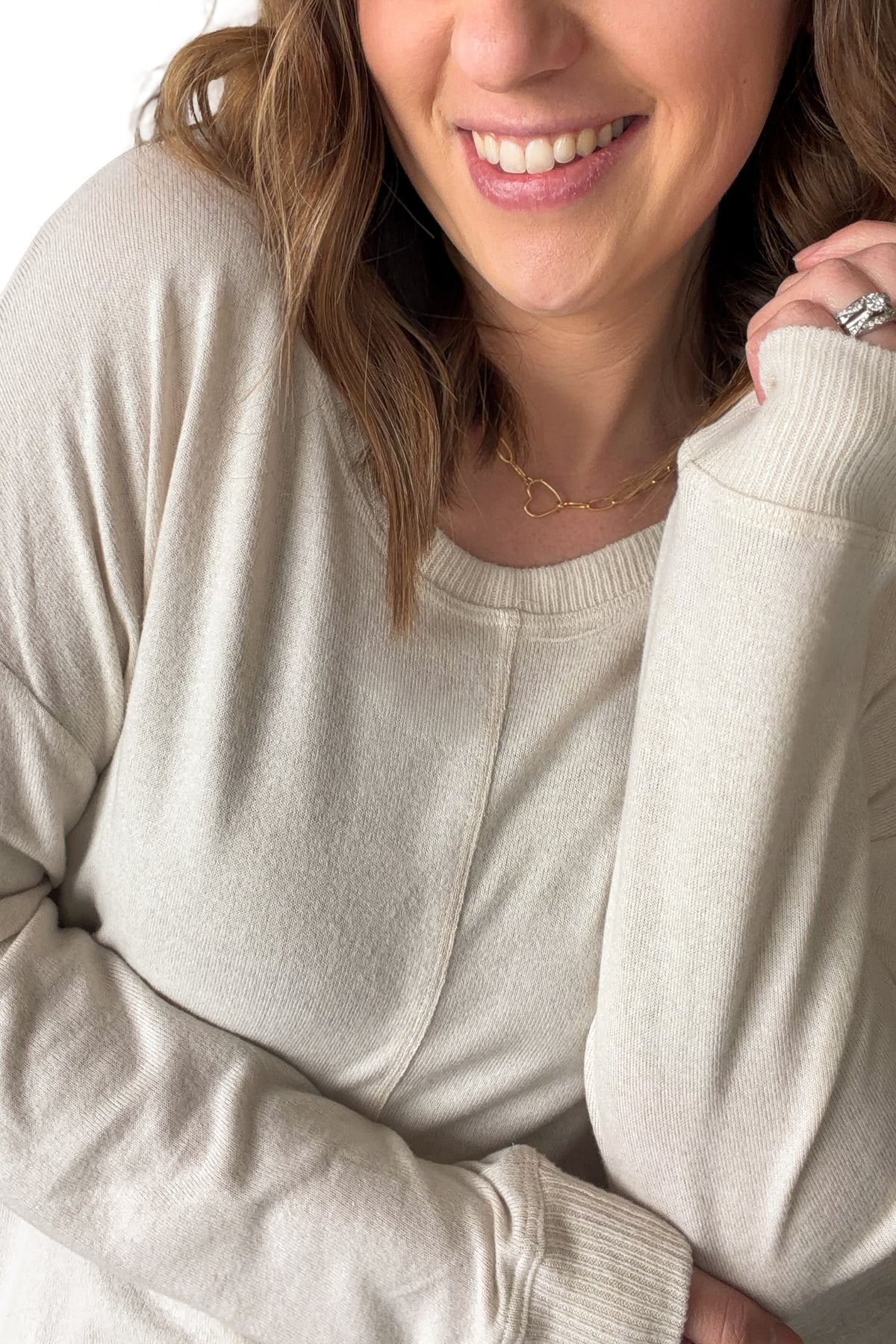 Close-up of a person wearing an ivory sweater with a neutral background