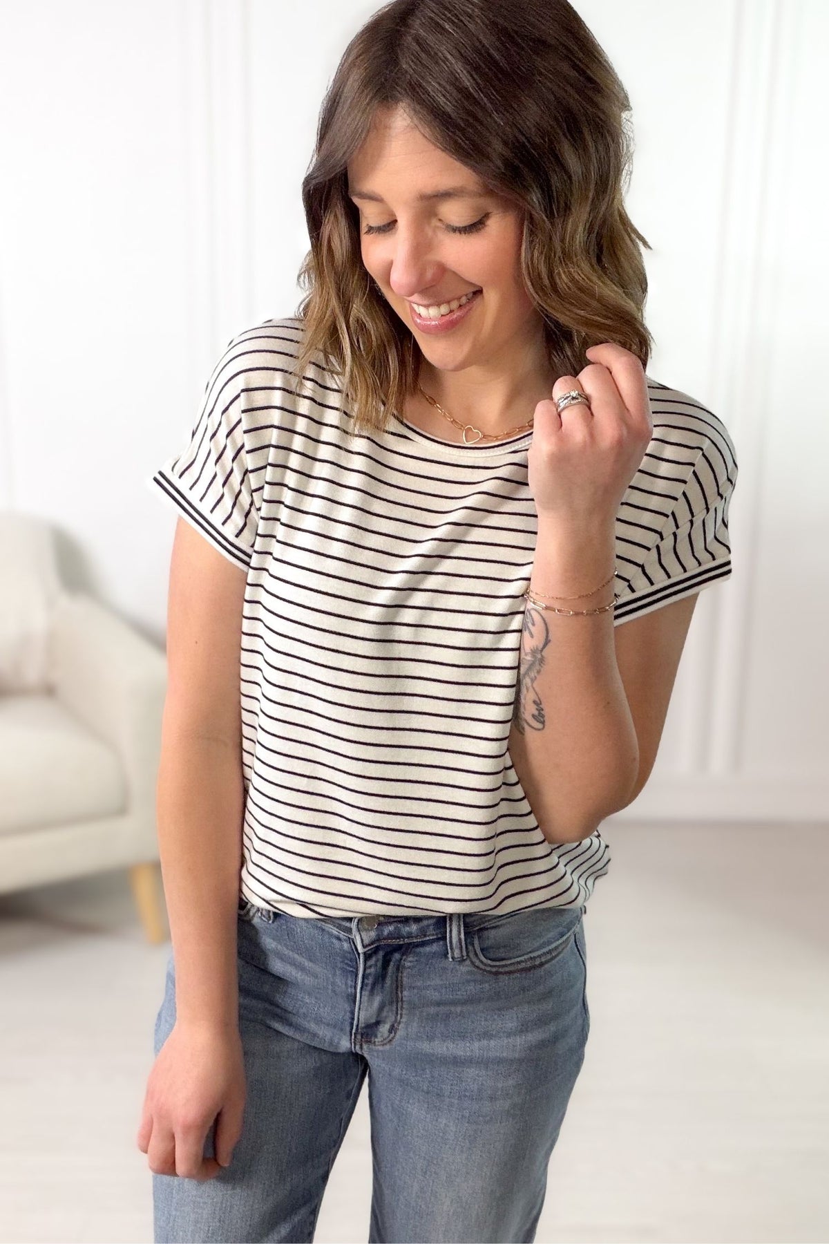 Woman wearing a white and black striped shirt and jeans indoors