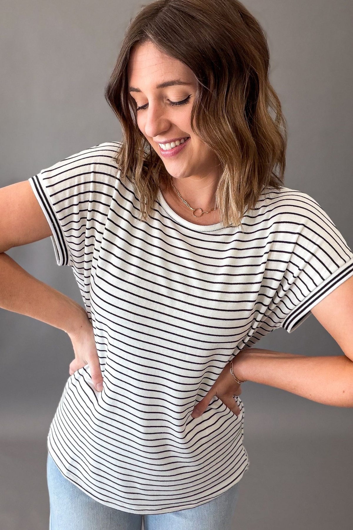 Woman wearing a black and white striped t-shirt against a gray background