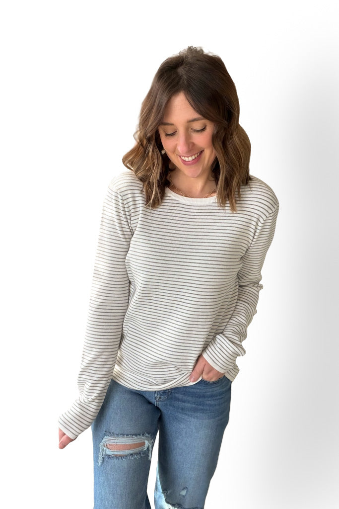 Woman wearing a striped long-sleeve top and jeans on a white background
