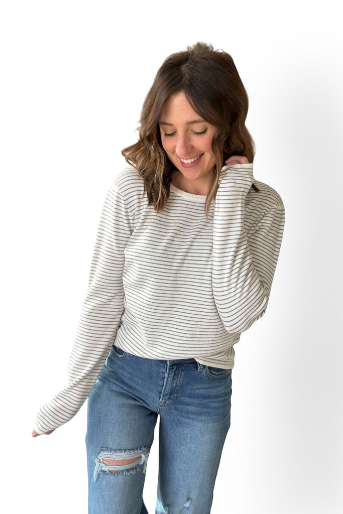 Woman wearing a striped long-sleeve top and jeans on a white background