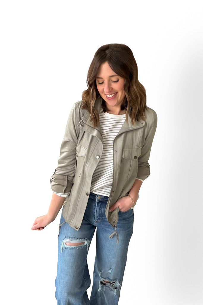 Woman wearing a green jacket and blue jeans on a white background