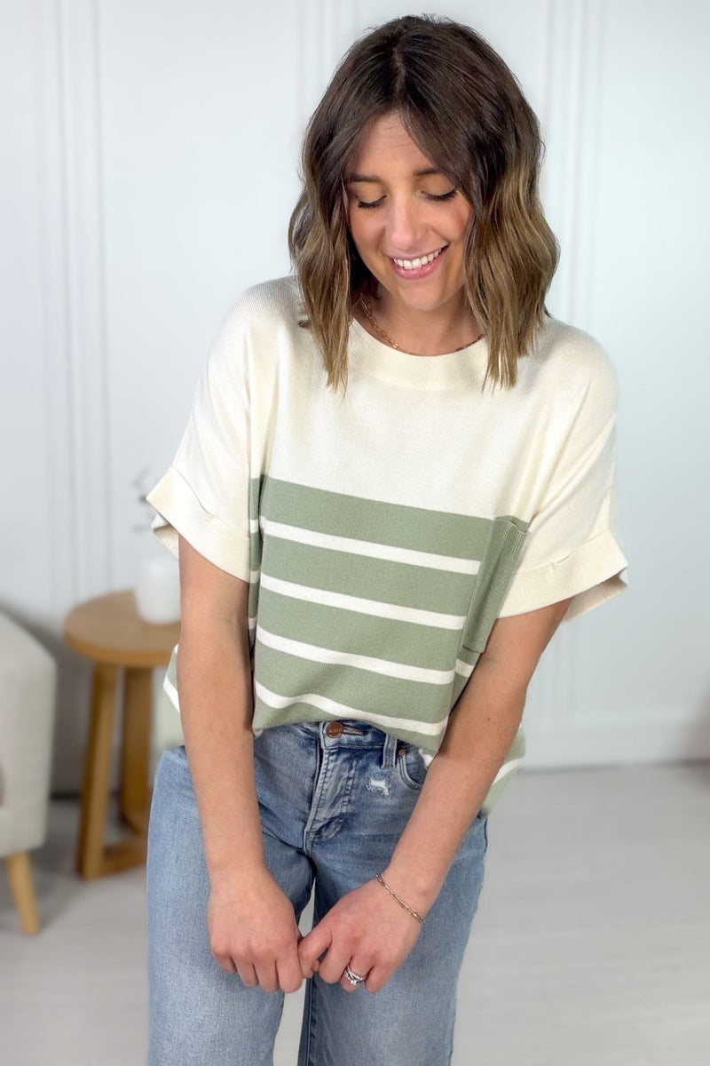 Woman wearing a sage striped shirt with a neutral background